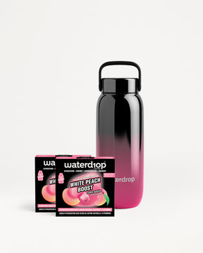 Litrena bočica s gradijentom crne u ružičaste boje uz dvije kutije Waterdrop.